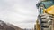 Panorama Close up of the tires of a bulldozer against snow peaked mountain and cloudy sky