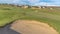 Panorama Close up view of a sand trap at a sunny golf course with houses in the distance