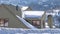 Panorama crop Snow covered pitched roof top of home against blurry mountain and sky in winter