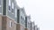 Panorama crop Upper storey of townhomes with brick wall vertical siding and snowy roofs