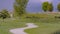 Panorama Curvy pathway small pond bench and trees on a grassy terrain under cloudy sky