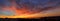 Panorama of dawn fire in the sky over a small seaside city. Golden red clouds just before the sunrise. Scenic landscape at sunrise