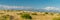 Panorama. Daytime landscape with a mountain range and a field with dry tall grass.