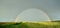 Panorama of double full rainbow over country road.