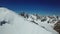 Panorama from a drone over a snowy cliff in the mountains. Two climbers climb the peak.