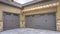 Panorama Exterior of a home with view of gray double garage doors and stone wall
