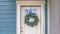 Panorama Facade of a home with a simple leafy wreath hanging on the white front door