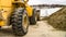 Panorama Focus on a yellow bulldozer with snowy mountain and cloudy sky in the background