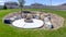Panorama frame Circular fire pit surrounded by rocks in the middle of the grassy yard of a home