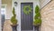 Panorama frame Gray front door of a home with green wreath and flanked by tall potted plants