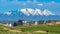 Panorama frame Houses on a grassy hill with view of lake and snow peaked mountain