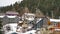 Panorama frame Mountain homes with snow covered roofs aginst coniferous trees and cloudy sky