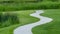 Panorama frame Pathway and pond on grassy terrain with homes lake and mountain background