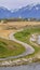 Panorama frame Paved pathway curving along the rocky and grassy lake shore under cloudy sky