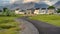 Panorama frame Paved road that curves through a field with multi storey homes in the distance