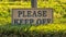 Panorama frame Please Keep Off sign against vibrant grasses and post of a wire fence