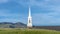 Panorama frame White steeple and rooftop of a church viewed from a grassy hill on a sunny day