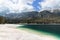 Panorama of the gentle shore of Tovel lake with emerald water and alpine mountain ranges covered with forest and snow