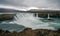 Panorama of Godafoss waterfall near Akureyri in the Icelandic highlands. Dramatic clouds and snow covered mountains in the back.