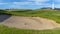 Panorama Golf course with sand bunker and vibrant fairway under blue sky on a sunny day