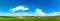 Panorama of a green field and sky. Sunny summer landscape of a European village