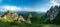 Panorama of green meadow with rocks and rocky mountains in romanian mountains in muntii ciucas with setting sun