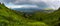 Panorama Green meadows with rocks in the Romanian mountains in Muntii Ciucas with a beautiful rainbow in the background