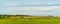 Panorama of hay bales on a farm along the ocean with the Confederation Bridge in the background