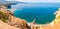 Panorama of high cliffs, Tyrrhenian sea bay with pure azure water, floating boats and ships, pebble beaches, rocky surroundings of