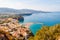 Panorama of high cliffs, Tyrrhenian sea bay with pure azure water, floating boats and ships, pebble beaches, rocky surroundings of