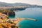 Panorama of high cliffs, Tyrrhenian sea bay with pure azure water, floating boats and ships, pebble beaches, rocky surroundings of