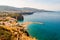 Panorama of high cliffs, Tyrrhenian sea bay with pure azure water, floating boats and ships, pebble beaches, rocky surroundings of