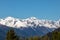 Panorama of high partly snowy mountains at blue sky