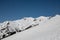 Panorama of high partly snowy mountains at blue sky