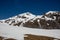 Panorama of high partly snowy mountains at blue sky