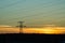 Panorama of high voltage power lines near water at sunset