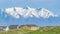 Panorama Homes and grassy field with snow covered mountain and blue sky background.