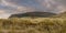 Panorama image, wooden fence and tall grass in foreground, Knocknarea hill in the background.