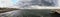 Panorama from the jetty to rough sea with scenic sky covered by clouds ready for the rain at distance a man alone looking the sea