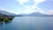 Panorama of lake, mountains and cottages near shore. Action. Top view of picturesque blue lake, shore with cottages for