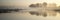 Panorama landscape of lake in mist with sun glow at sunrise