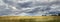 panorama of landscape with meadow with tall grass, cloudy sky