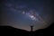 Panorama landscape with milky way, Night sky with stars and silhouette of a standing sporty man with raised up arms on high mount