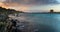 Panorama landscape with rocky shore at sunset and the Torrre de la Pelosa watchtower in northern Sardinia