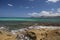 Panorama landscape scenic view of isolated deserted yellow rocky beach with blue turquoise sea water and sky with white clouds and