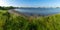 Panorama landscape of a small ocean lagoon with a sandy beach and a wildflower meadow under a blue sky