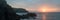 Panorama landscape vibrant sunset over rocky coastline