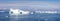 Panorama of large icebergs wirh arches, part of which has fallen into the water in Disko Bay, Greenland