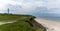 Panorama of the lighthouse and grassy sand dunes above the white sand beach at Hirtshals in northern Denmark