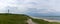 Panorama of the lighthouse and grassy sand dunes above the white sand beach at Hirtshals in northern Denmark